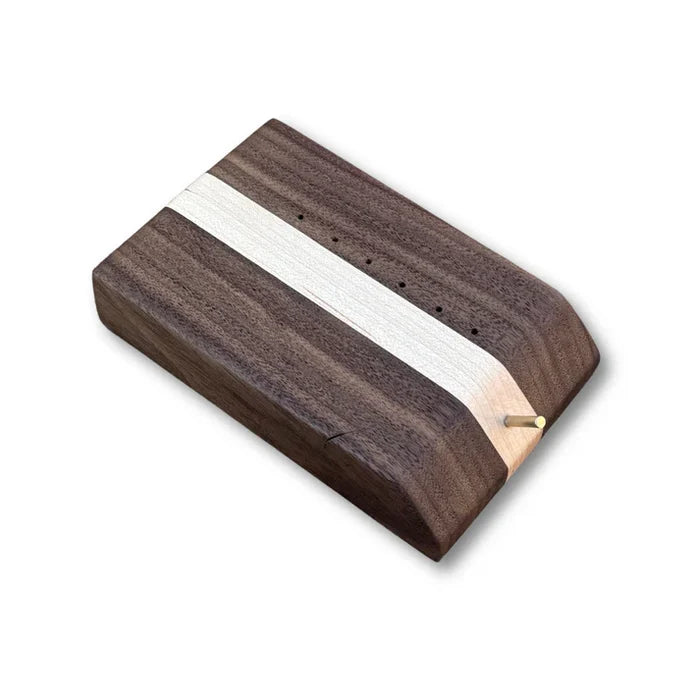 Temperance & Penn Clark's Dubbing Block made of smooth wood with a central lighter stripe, featuring multiple small holes and a wooden peg for organizing fishing tackle materials.