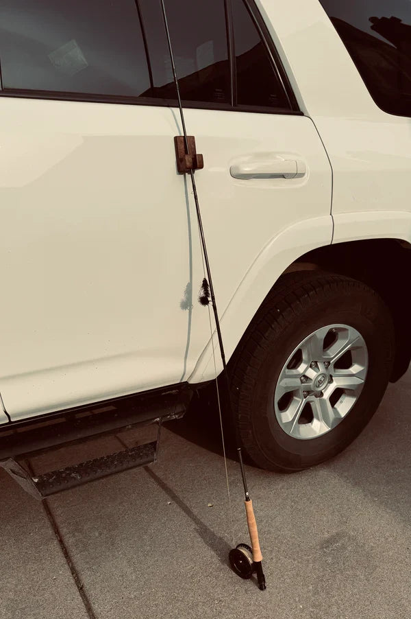 Temperance & Penn Gear Hook-Magnetic attached to a white vehicle door holding two fishing rods upright, showcasing a practical fishing pole holder for fishing tackle.