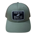 Thorne Bros Fly Fishing Logo Richardson 112 Trucker Cap in olive green with a black and white embroidered patch featuring a fly fishing lure design, mesh back, and curved brim.