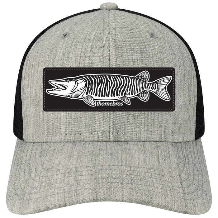 Front view of a gray and black mesh cap featuring a rectangular patch with a detailed black and white musky fish illustration and the text Thorne Bros. Legacy Mid-Pro Large Musky Patch on the front panel.