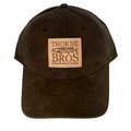 Brown waxed fabric baseball cap featuring a tan leather patch with "Thorne Bros. Logo Richardson Leather Patch" embossed along with a fish design and "Custom Rod & Tackle" text.