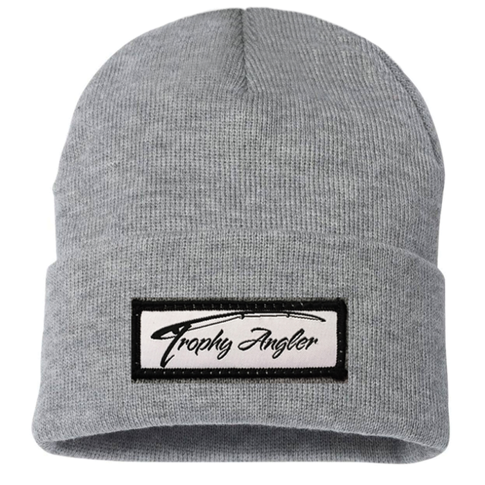 Trophy Angler Knit Stocking Cap in light grey knit fabric with a folded cuff featuring a stitched rectangular patch embroidered with "Trophy Angler" text in black script.