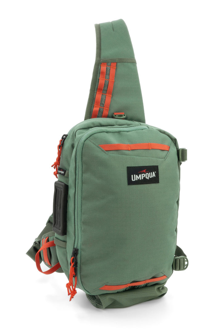 Green Umpqua Northfork Sling Pack with orange accents, featuring multiple zippered compartments, adjustable strap, and durable fabric designed for fishing tackle organization.