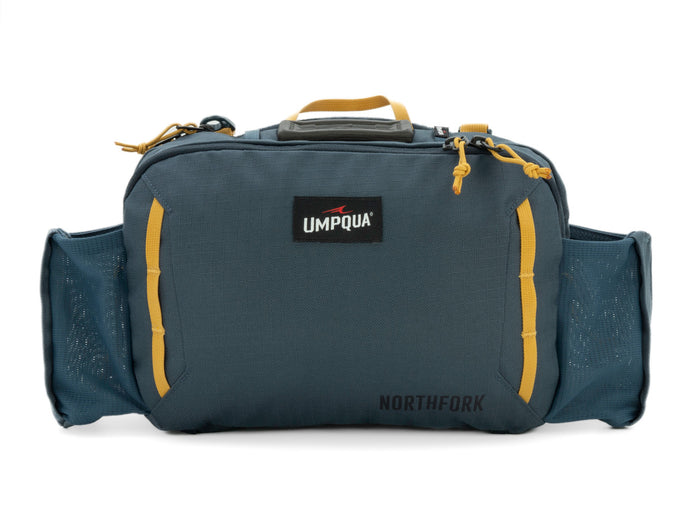 Umpqua Northfork Waist Pack in dark cobalt blue with yellow accents, featuring a central compartment, two mesh side pockets, and a top handle for fishing tackle organization.