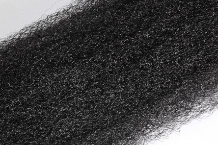 Close-up view of black fibrous material strands for fly tying, showing the texture and detail of Wapsi Fuzzy Fiber used in fishing tackle and lure making.
