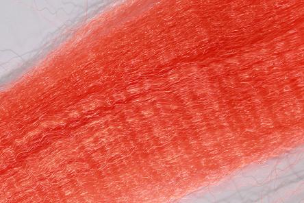 Close-up of bright orange synthetic fibers from Wapsi Fuzzy Fiber used for creating fishing lures and tackle in fly fishing.