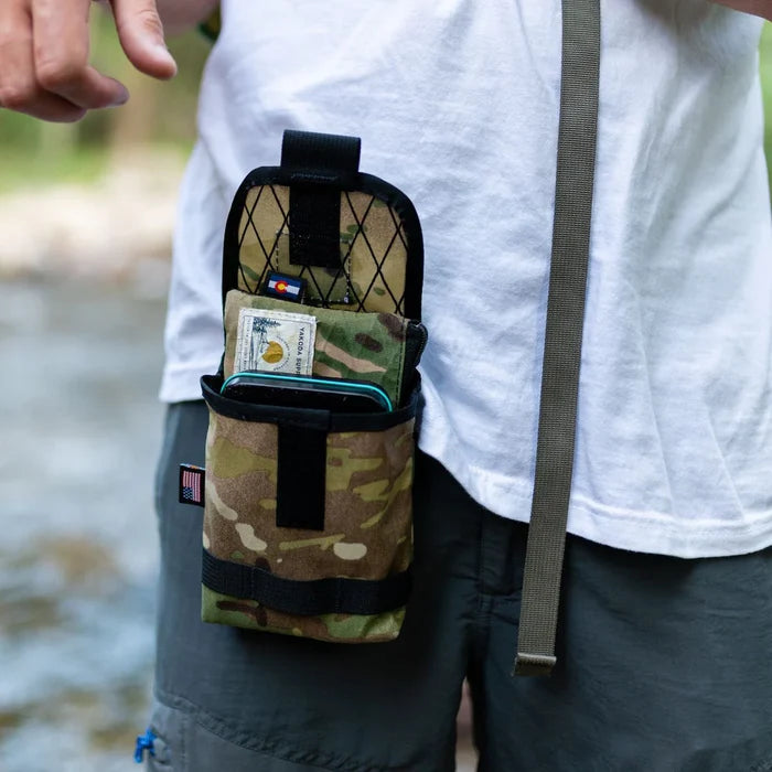Yakoda Utility Pouch in camouflage pattern worn on hip, showing open top with compartments holding a wallet and other small items, designed for outdoor and fishing use.