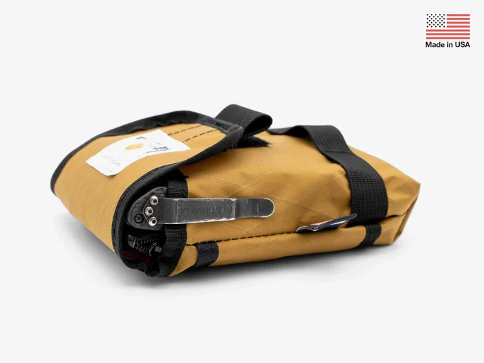 Yakoda Utility Pouch in coyote brown, folded with black straps and a metal clip, designed for organizing fishing tackle and gear, made in the USA.