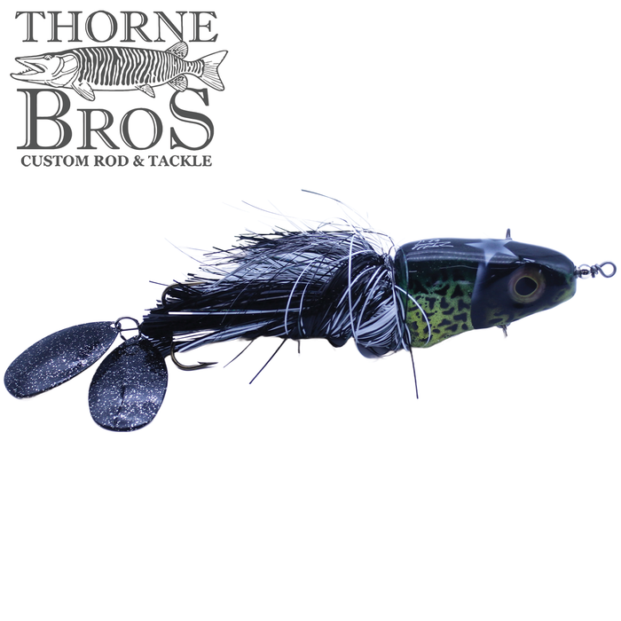 Zilla Baits Metal Head fishing lure with a black and green painted head, black and white feather skirt, and two black metal spinner blades for attracting fish.